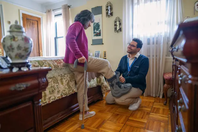 Physical therapist adjusting medical boot for older female patient