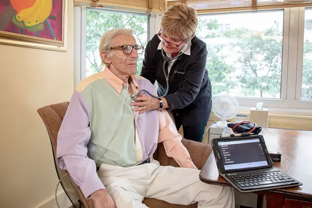 home health aide listening to heart of senior man