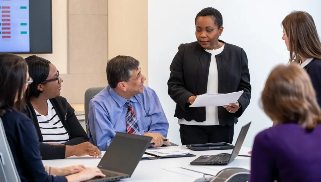 team members gathered around a table talking to one another