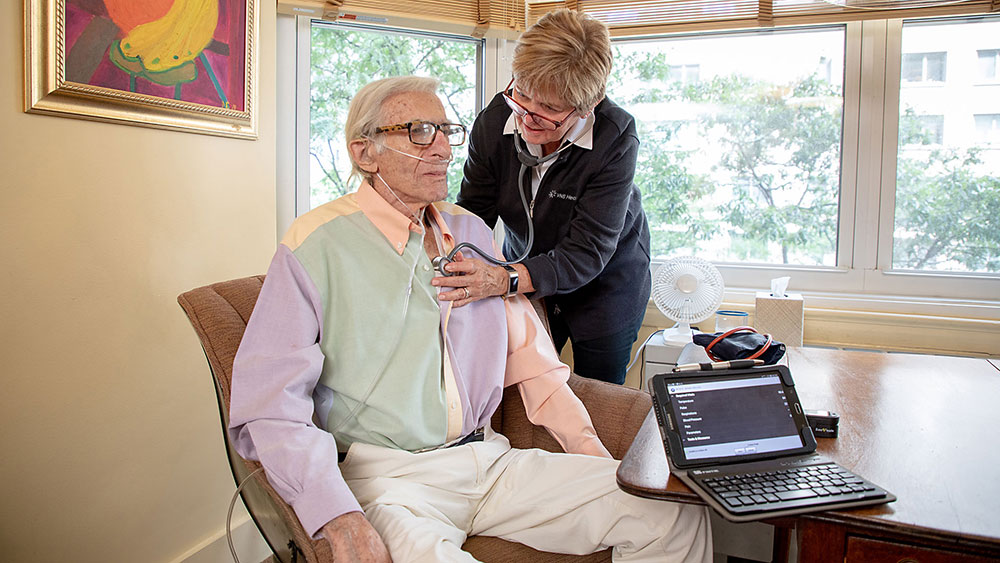home health aide listening to heart of senior man