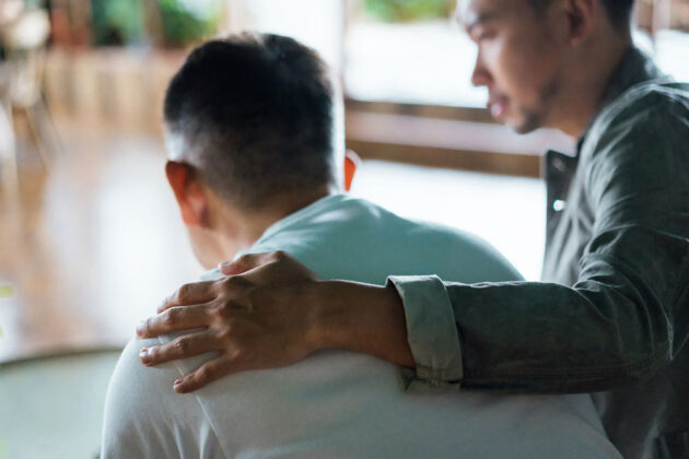 Adult son comforting elderly father