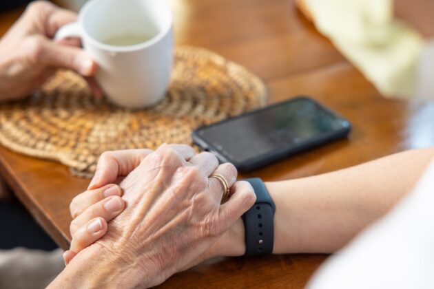 Hospice patient holding hands with loved one.